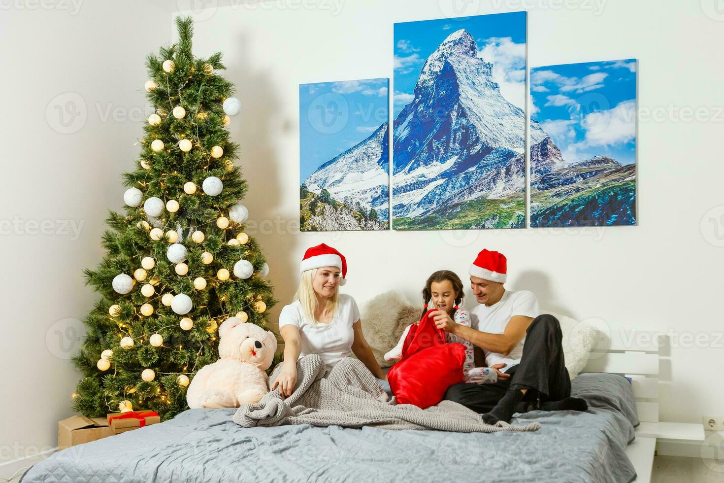 feliz família às lar. mãe, pai e criança deitado dentro a cama com Natal presente. inverno feriado conceito foto