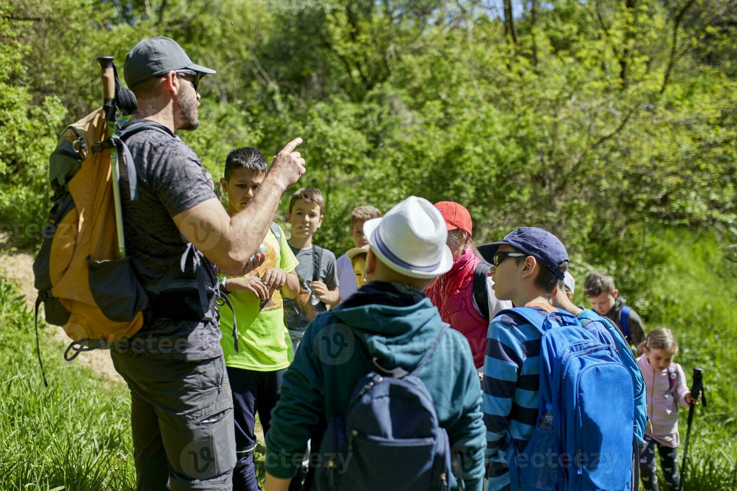 homem falando para crianças em uma campo viagem em trilha foto