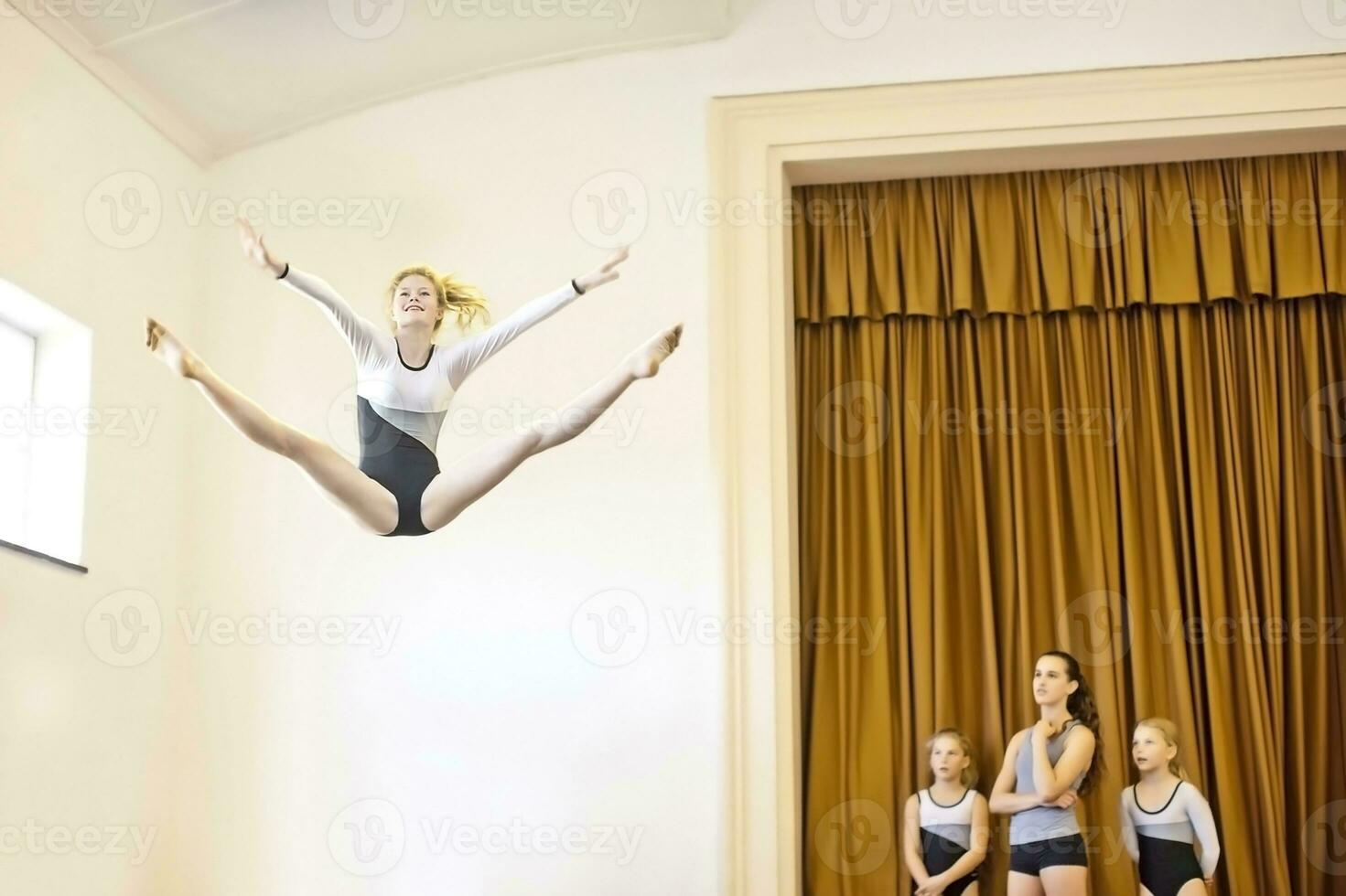 menina dentro ginástica equipamento fazendo aéreo saltar com três meninas assistindo foto