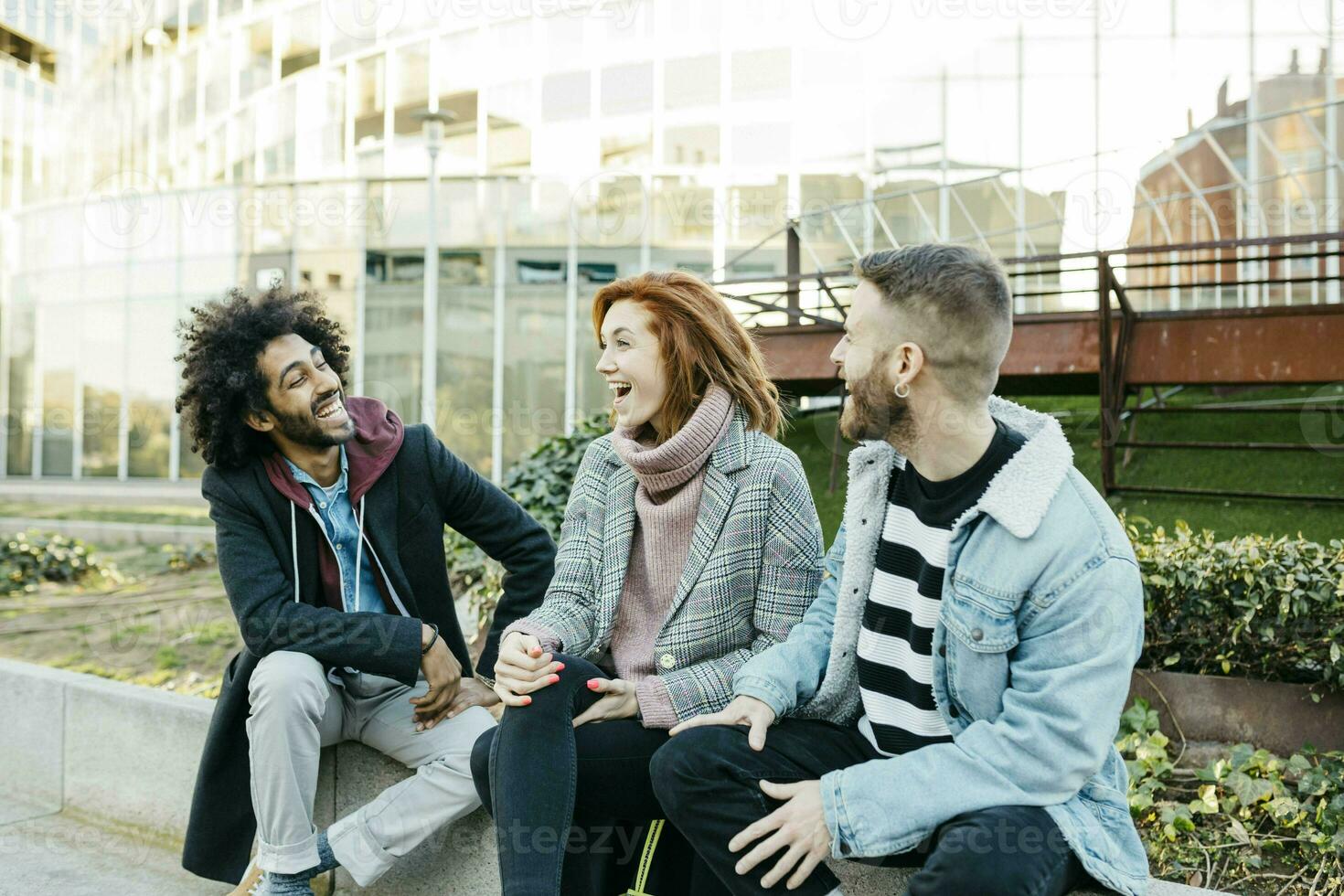 três feliz amigos sentado dentro a cidade falando foto