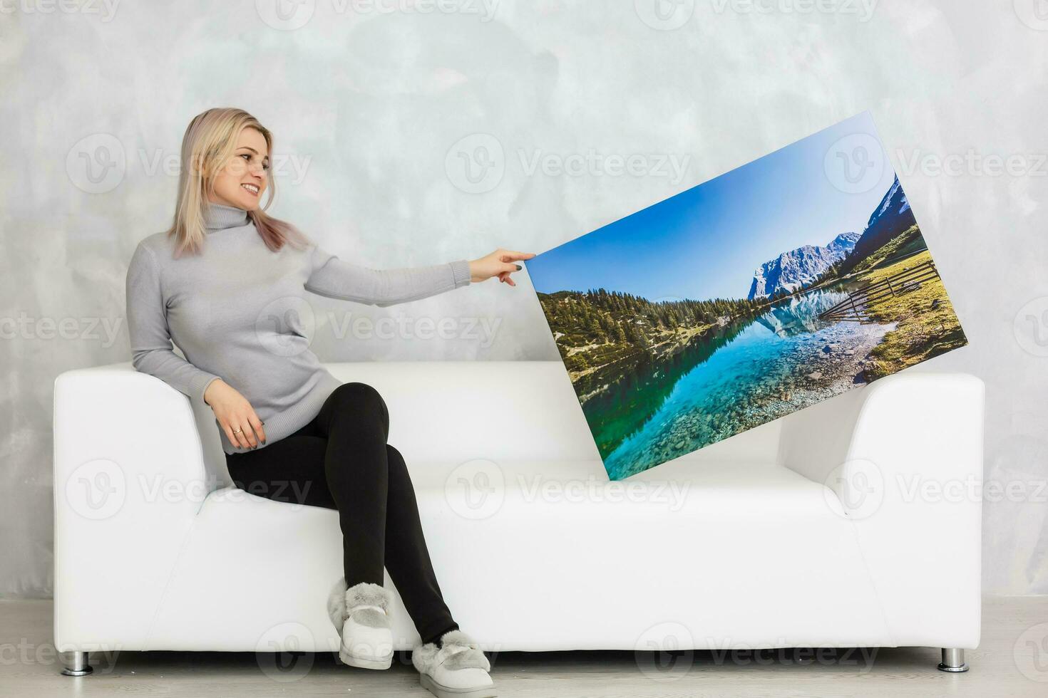 menina suspensão uma quadro, Armação tela de pintura em uma cinzento parede foto