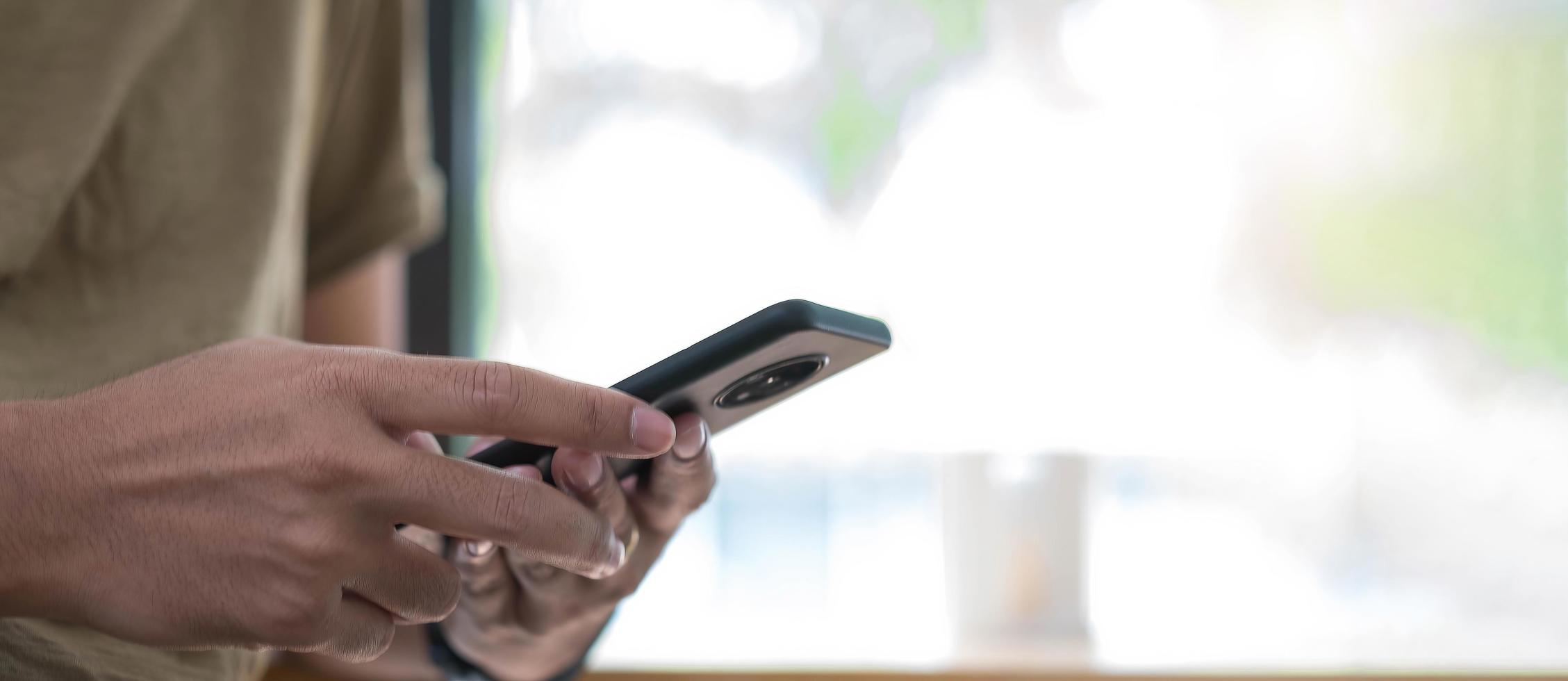 homem segurando smartphone perto da janela foto