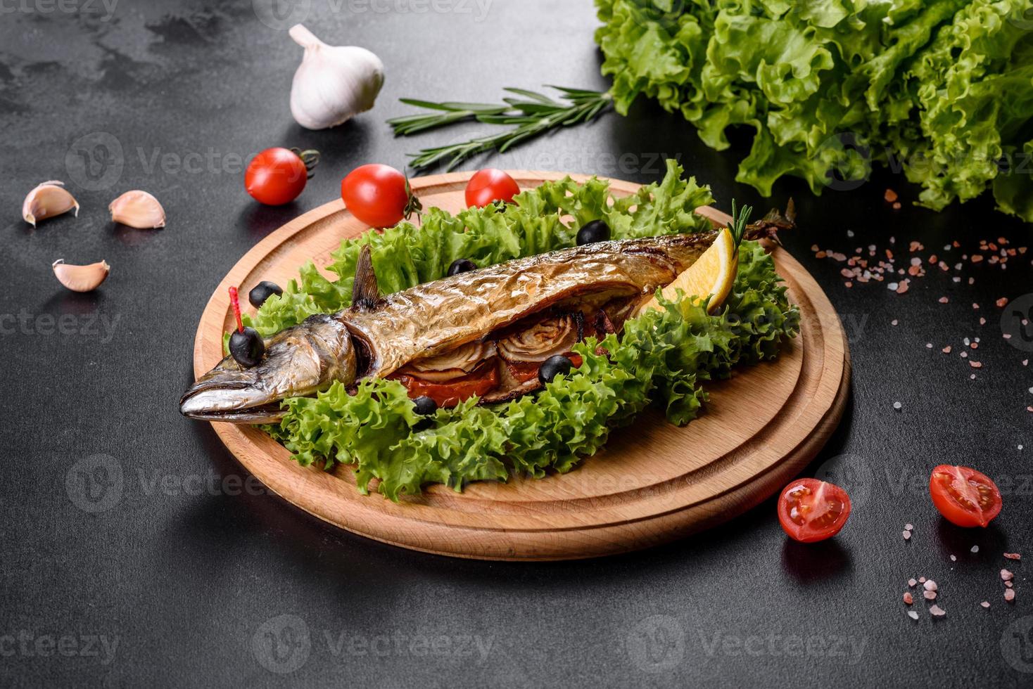 cavala assada com legumes em uma placa de madeira com limão foto