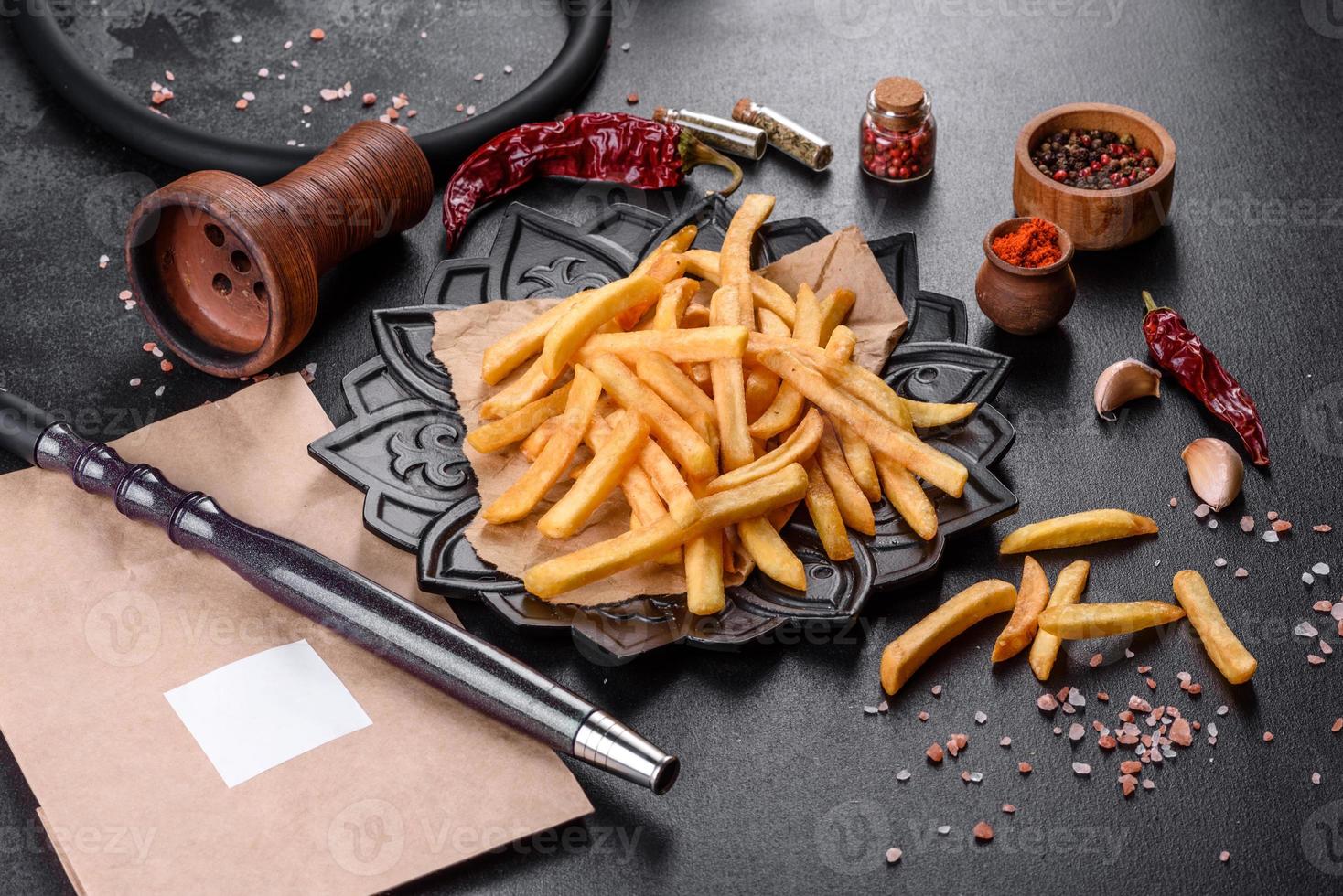 saborosas batatas fritas fritas com sal e especiarias em um fundo escuro foto