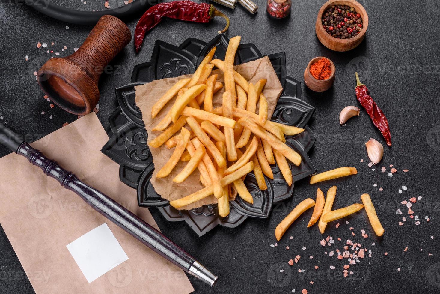 saborosas batatas fritas fritas com sal e especiarias em um fundo escuro foto