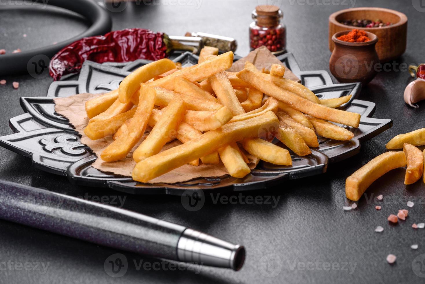 saborosas batatas fritas fritas com sal e especiarias em um fundo escuro foto