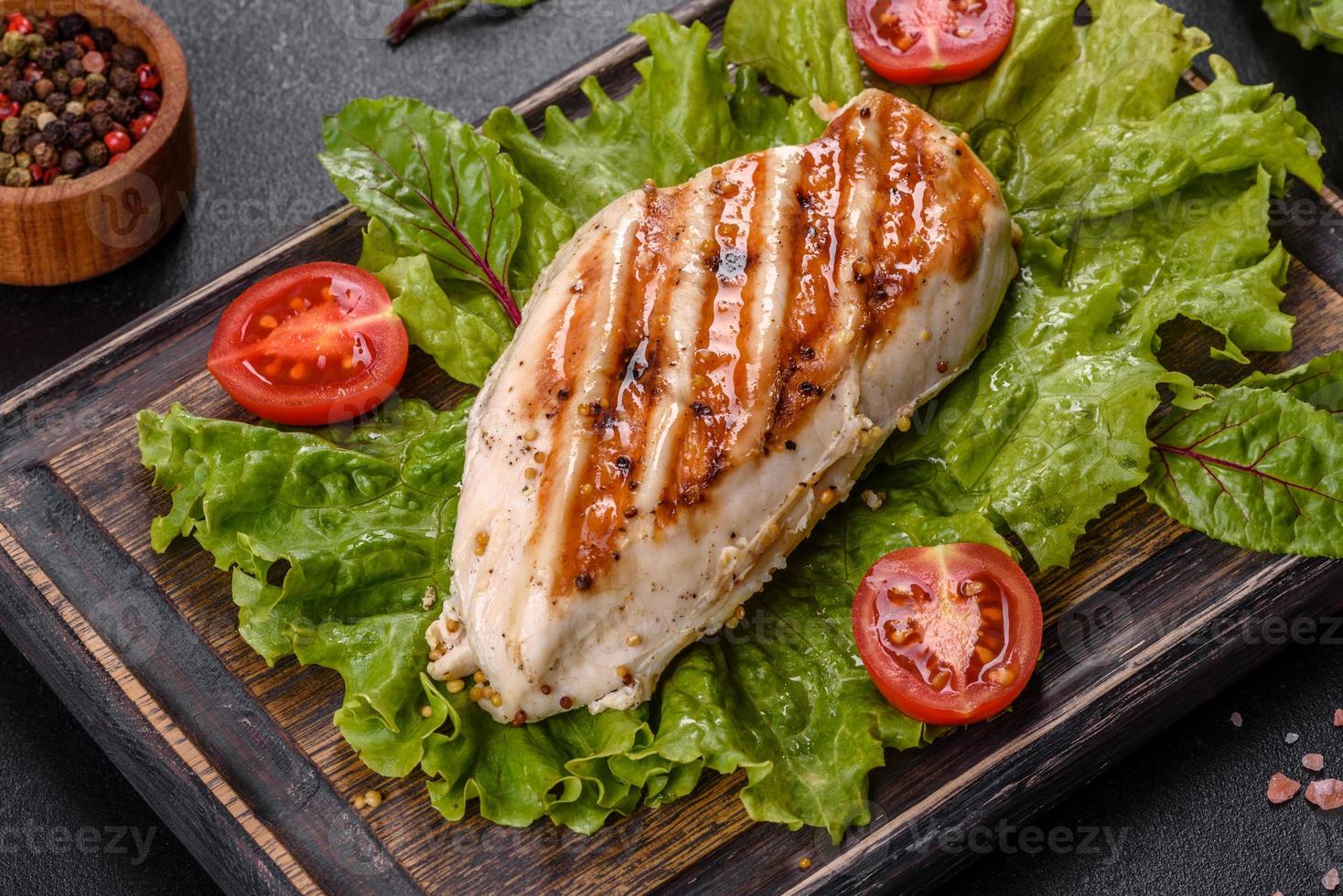 pedaços de frango, tomate e folhas de alface em um fundo escuro de concreto foto