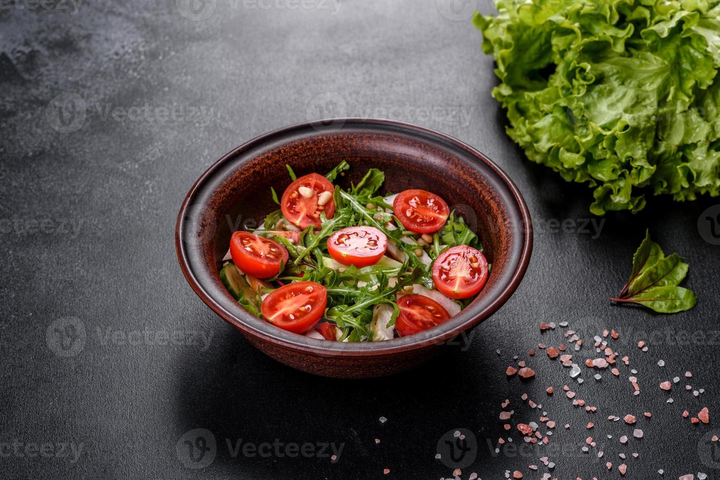 pedaços de frango, tomate e folhas de alface em um fundo escuro de concreto foto