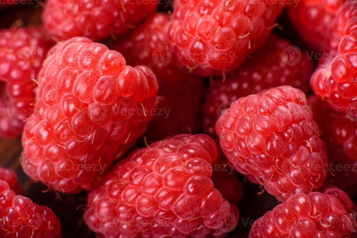 deliciosas framboesas vermelhas suculentas frescas em uma mesa escura foto
