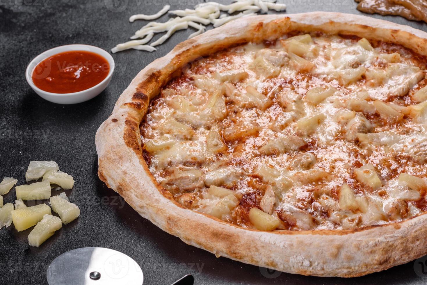 deliciosa pizza italiana fresca com frango, tomate e abacaxi em um fundo escuro de concreto foto