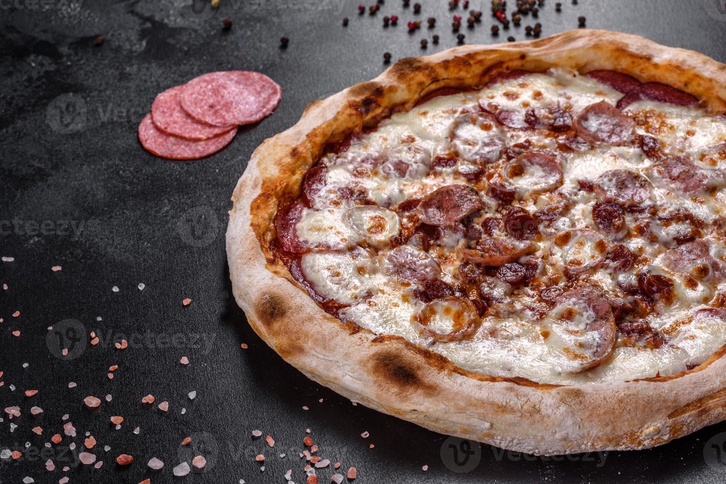 deliciosa pizza italiana fresca com quatro tipos de carne em um fundo escuro de concreto foto