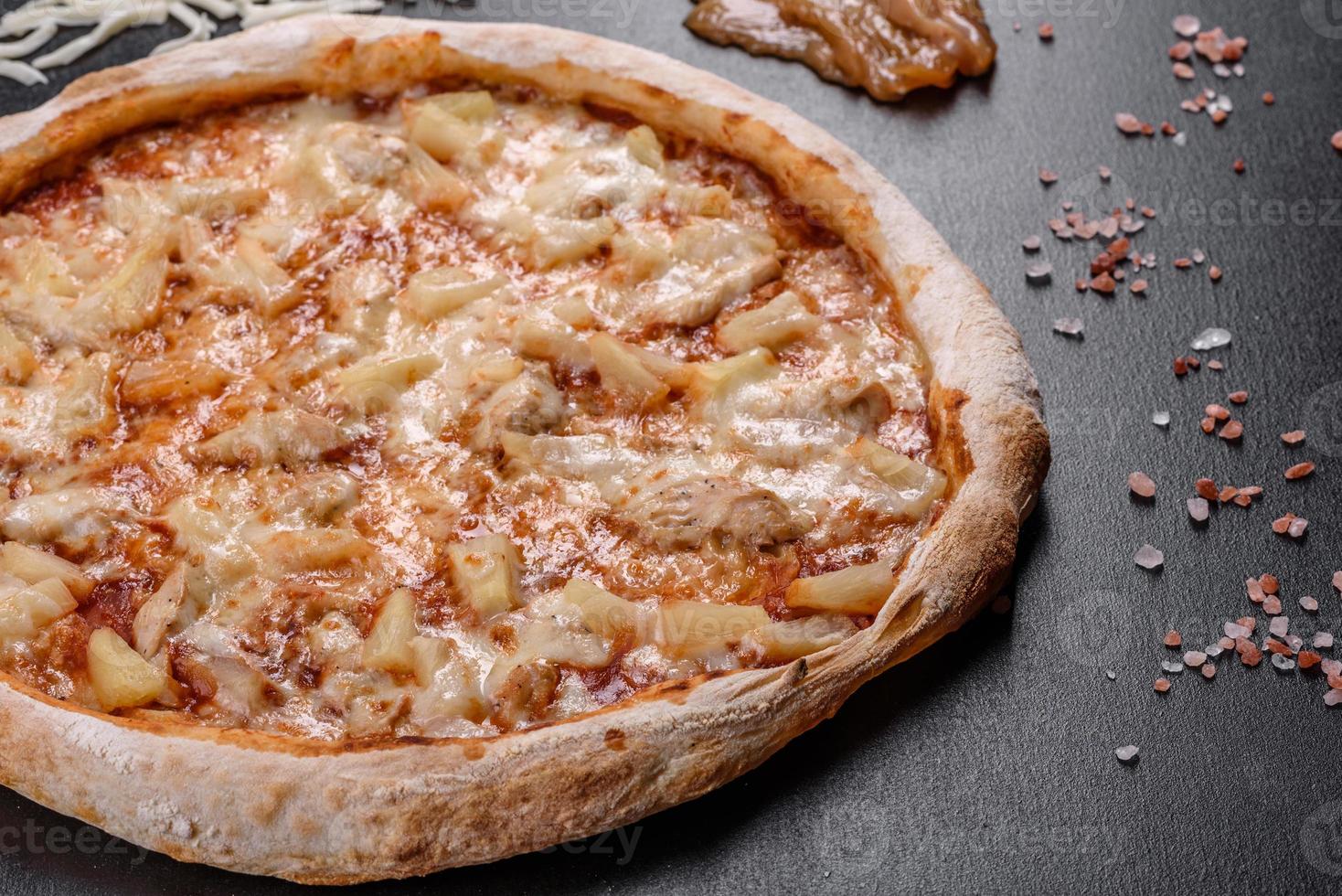 deliciosa pizza italiana fresca com frango, tomate e abacaxi em um fundo escuro de concreto foto