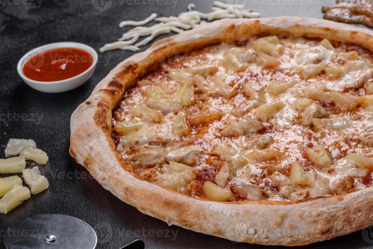 deliciosa pizza italiana fresca com frango, tomate e abacaxi em um fundo escuro de concreto foto