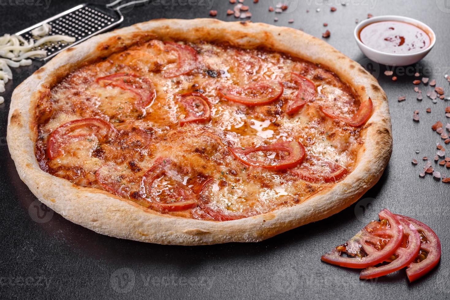 deliciosa pizza italiana fresca com cogumelos e tomates em um fundo escuro de concreto foto