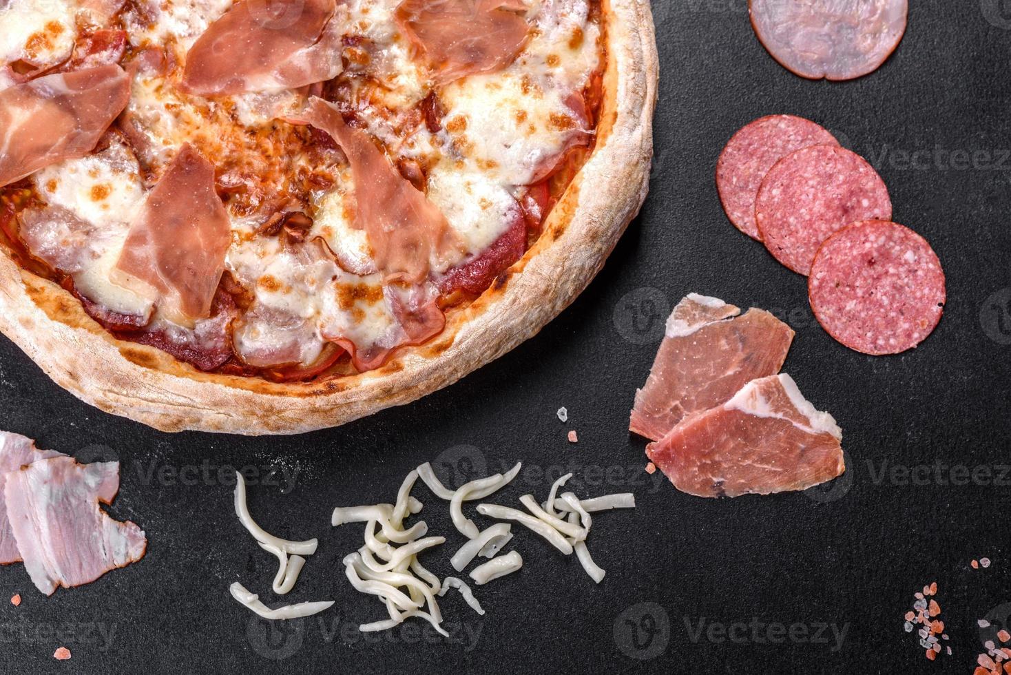 deliciosa pizza italiana fresca com presunto em um fundo escuro de concreto foto