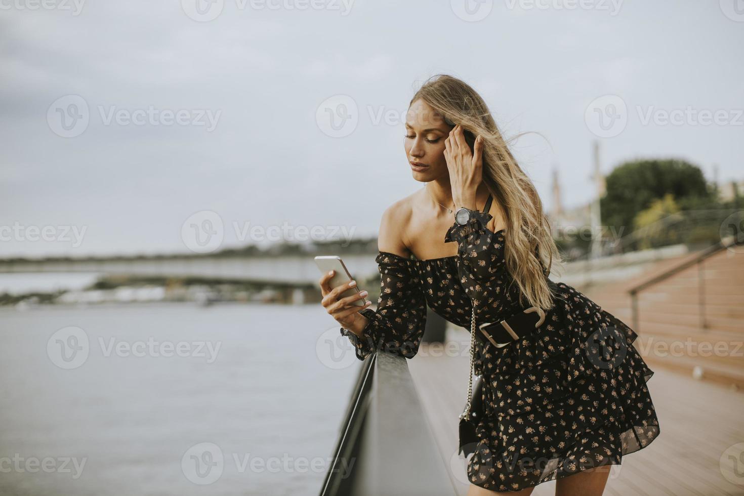 jovem morena de cabelos longos em pé à beira do rio foto