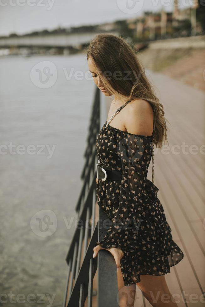 jovem morena de cabelos longos em pé à beira do rio foto