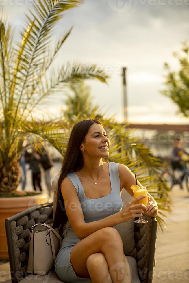 jovem bebendo suco de laranja no café da rua foto