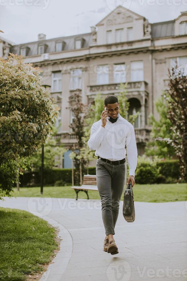 jovem empresário afro-americano usando um telefone celular em uma rua foto