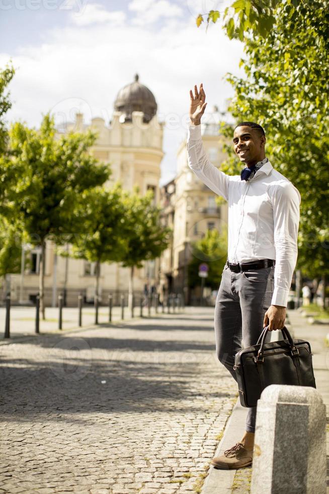 jovem empresário afro-americano esperando um táxi em uma rua foto