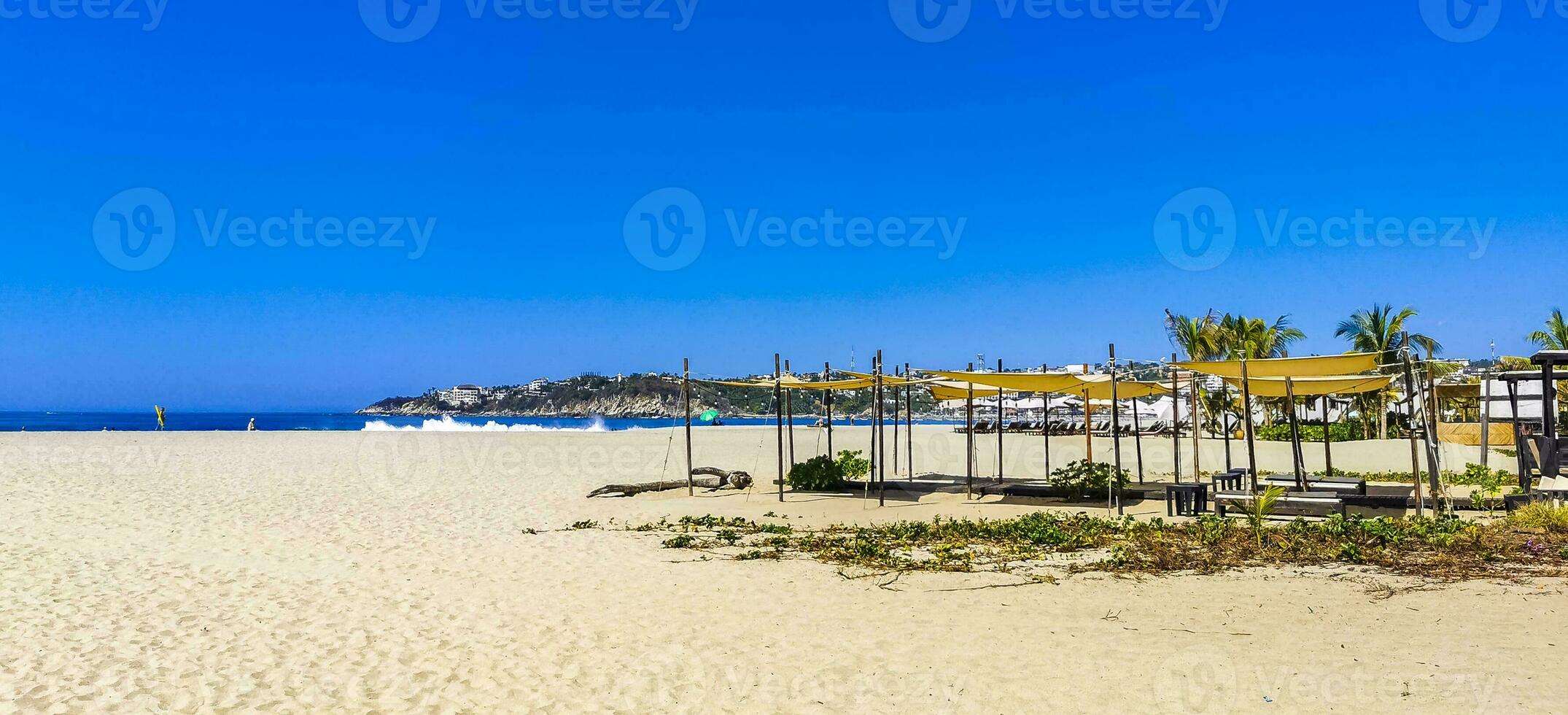 Palmeiras guarda-sóis Sol espreguiçadeiras de praia pessoas zicatela porto escondido México. foto