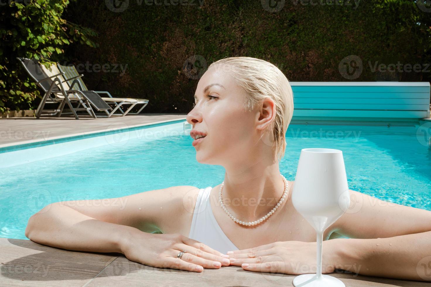 jovem linda garota sexy nadando na piscina privada e relaxando ao sol foto