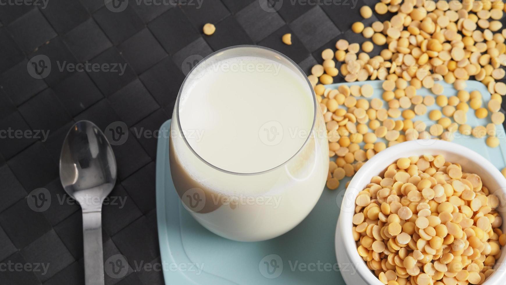 leite de soja sem açúcar adicionado em um copo em uma placa de plástico de cor verde foto