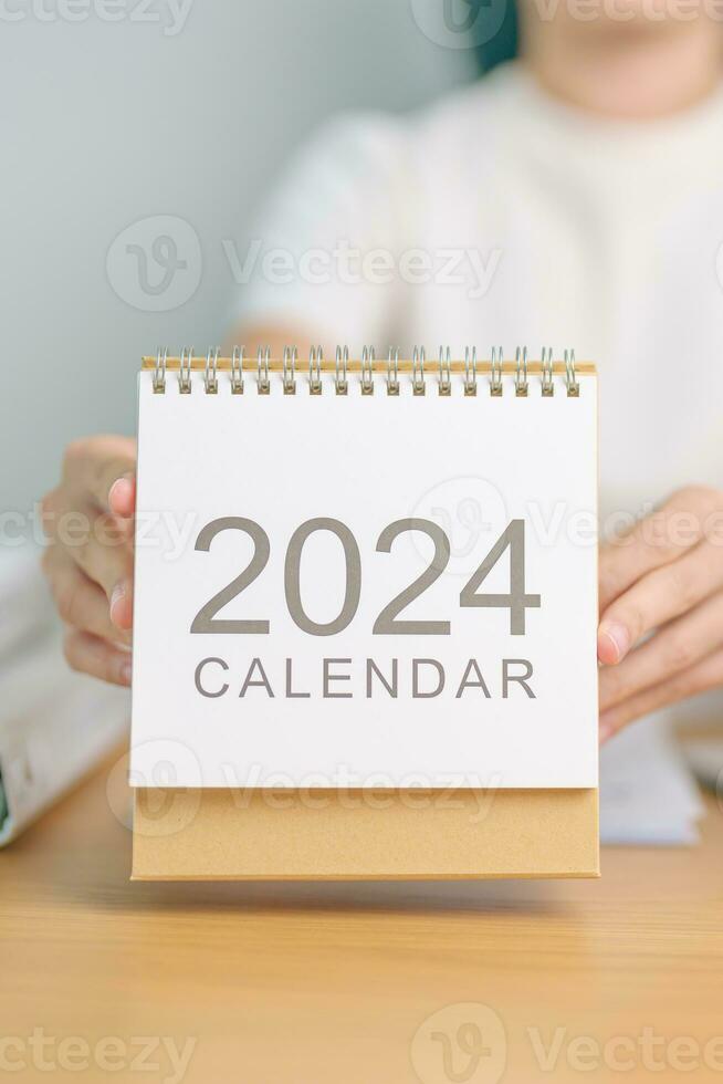 2024 ano calendário em mesa com o negócio mulher usando computador portátil computador. contagem regressiva, feliz Novo ano, resolução, metas, plano, Ação, missão e financeiro conceito foto