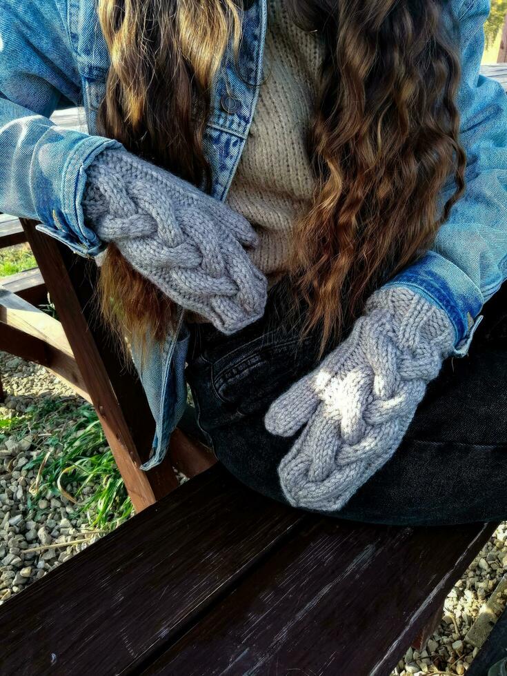 fêmea mãos dentro de lã luvas em uma Banco dentro a parque. foto