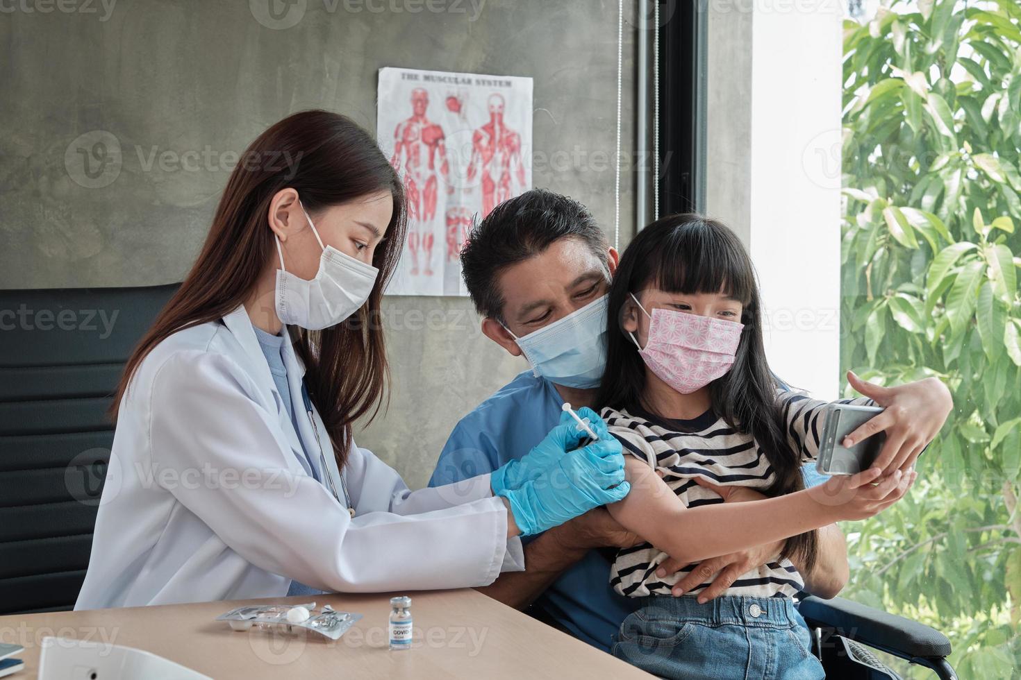 menina asiática tomando uma selfie enquanto um médico está se vacinando. foto