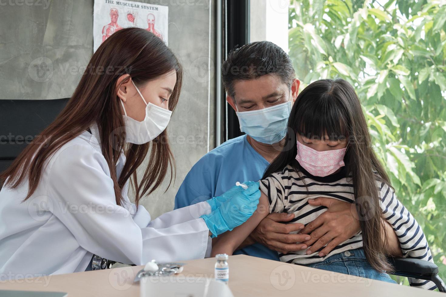 médica vacinando menina asiática na clínica de pediatria. foto