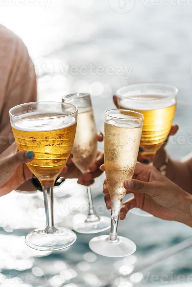 mão segurando um copo bebendo vinho no fundo do mar do sol. foto