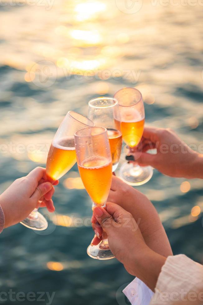 mão segurando um copo bebendo vinho no fundo do mar do sol. foto