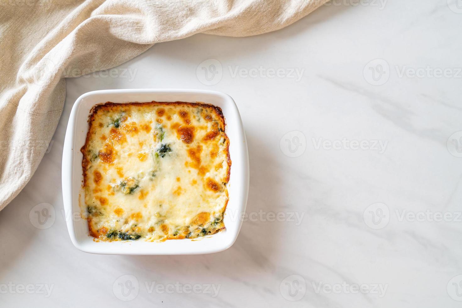 espinafre assado e lasanha de espinafre assada com queijo em prato branco foto
