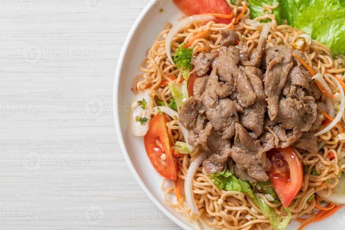 Salada picante de macarrão instantâneo com carne de porco no prato branco - comida asiática foto