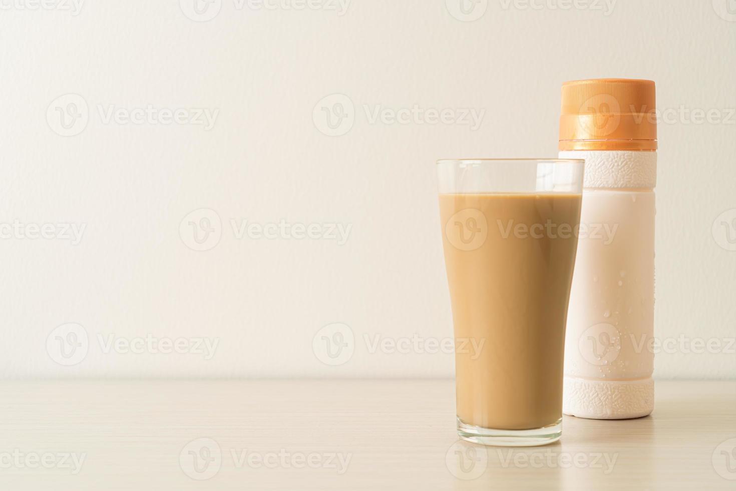 copo de café com leite com garrafas de café prontas para beber na mesa foto