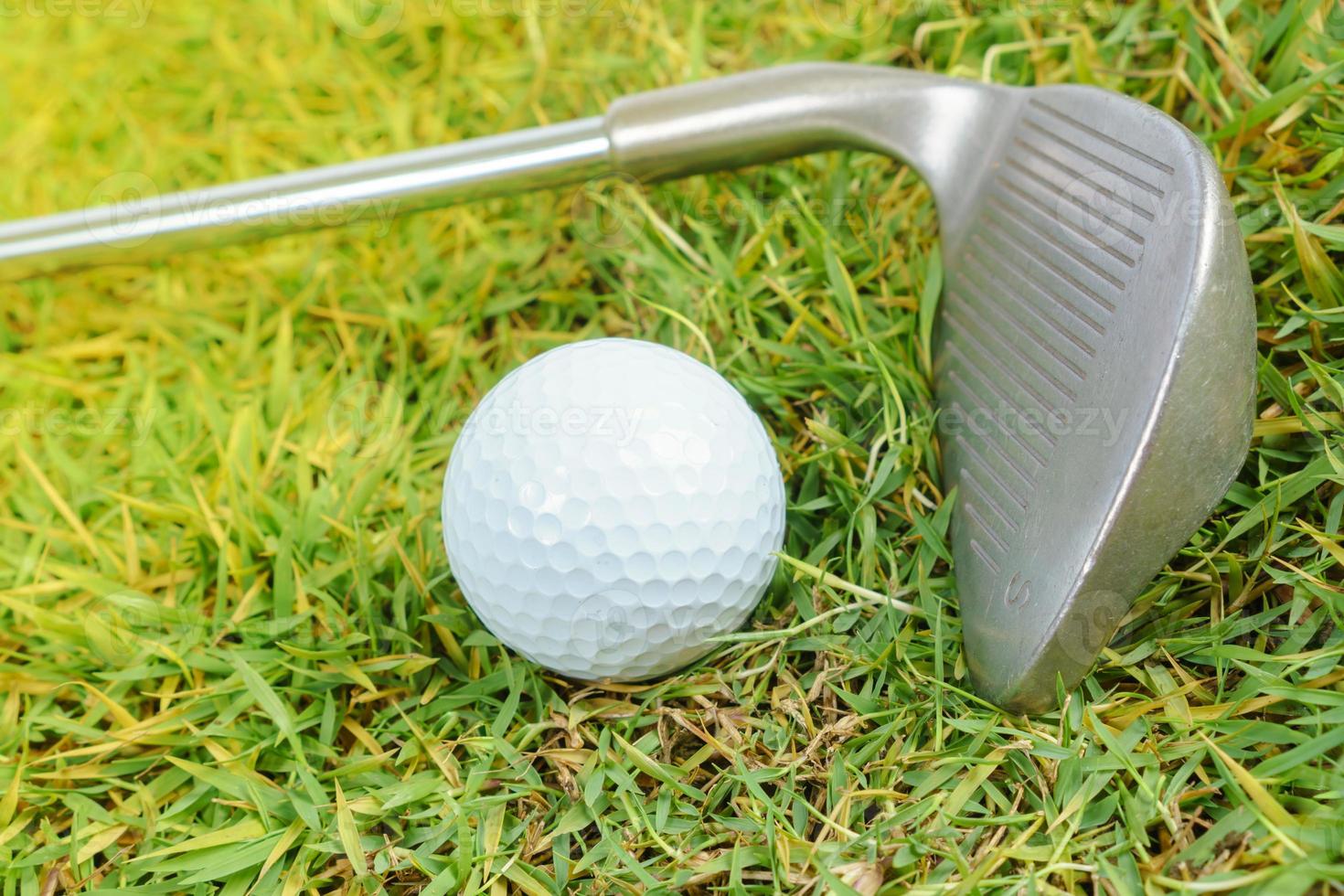 tacos de golfe e bola de golfe no fundo da grama verde foto
