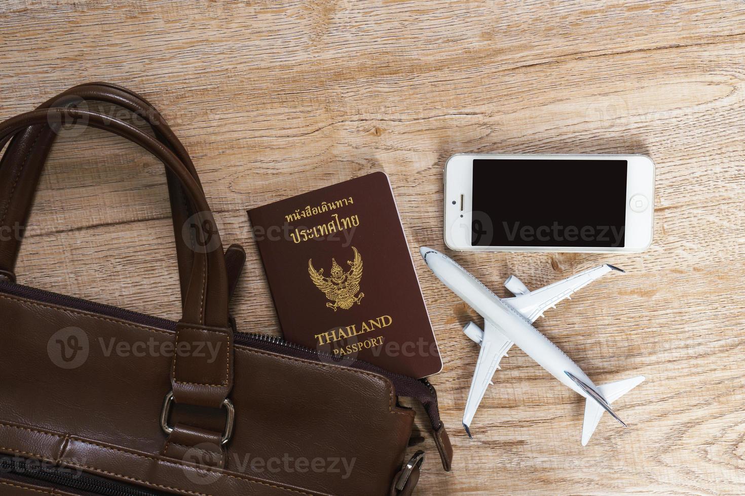 bolsa de couro e pequeno modelo de avião no fundo da placa de madeira foto