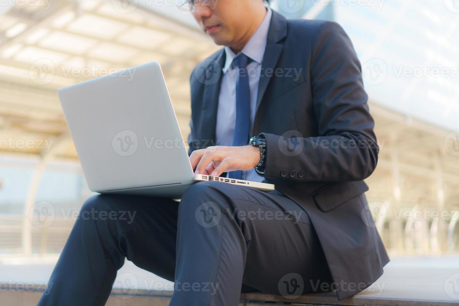 empresário sentado nas pegadas com um laptop foto