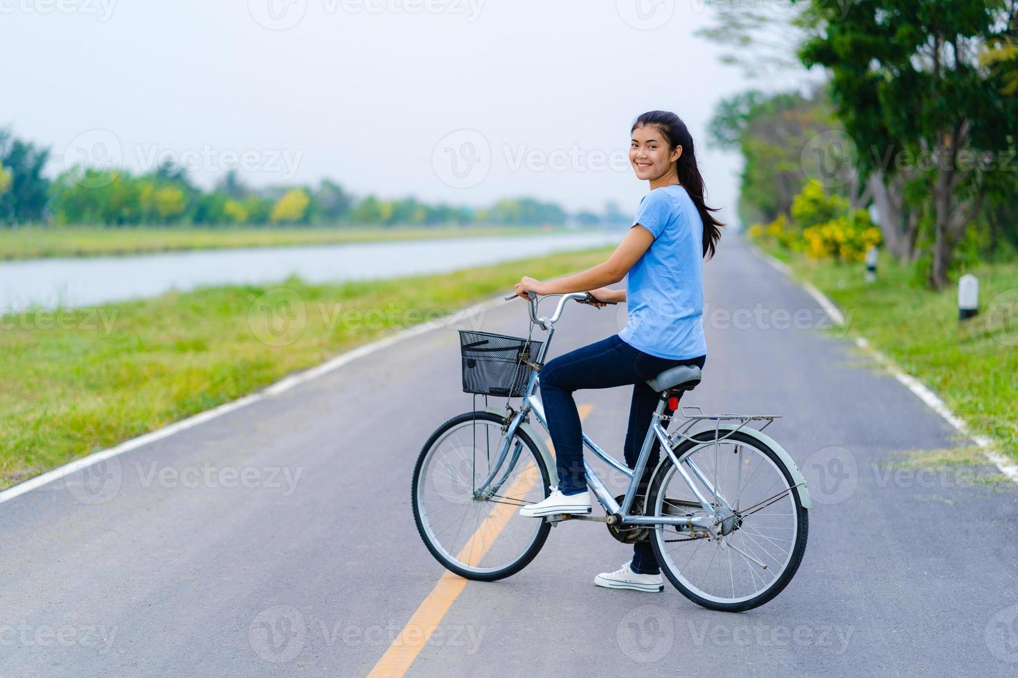 menina com bicicleta, mulher andando de bicicleta na estrada em um parque foto