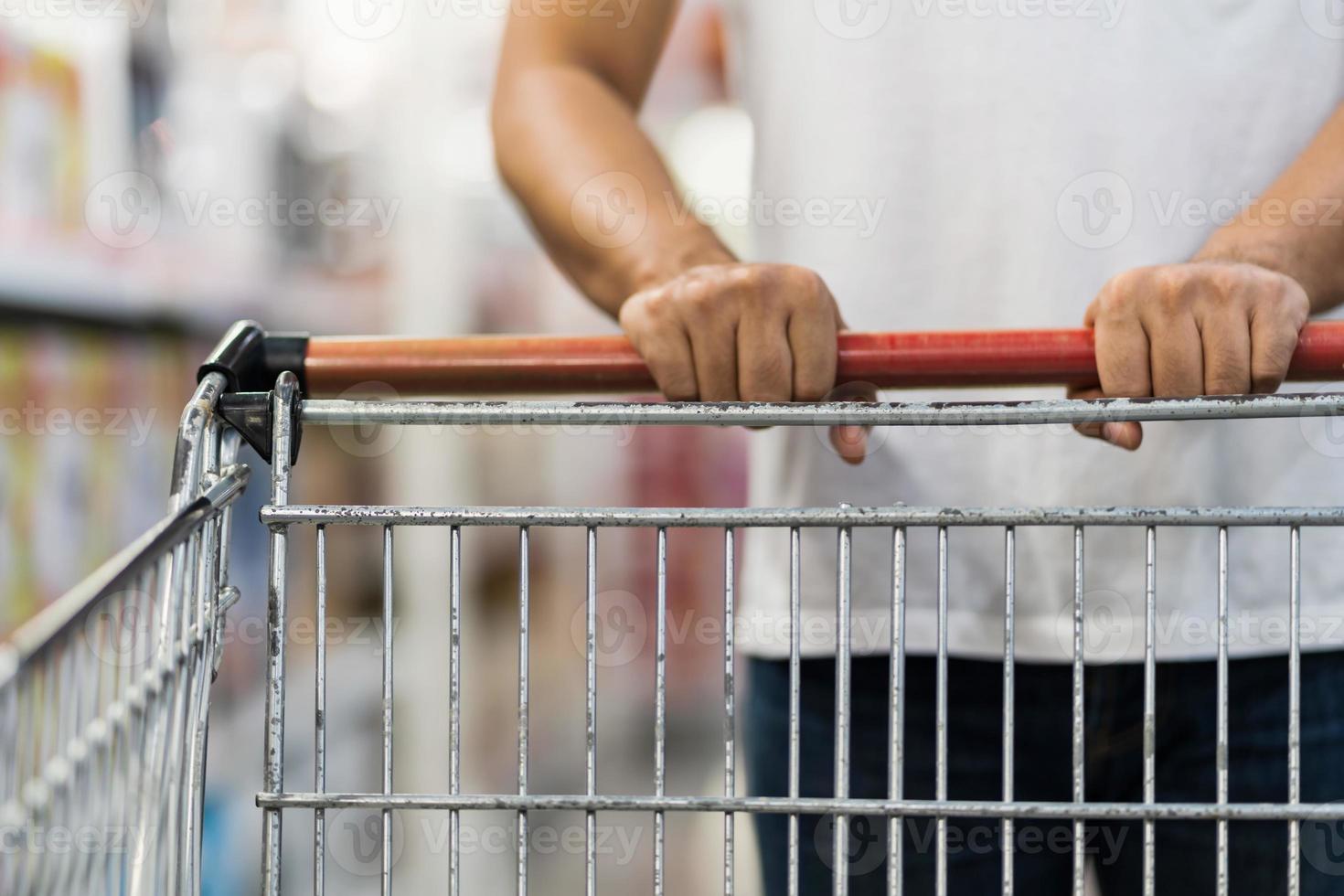 close-up de homem empurrando carrinho de compras em um supermercado foto