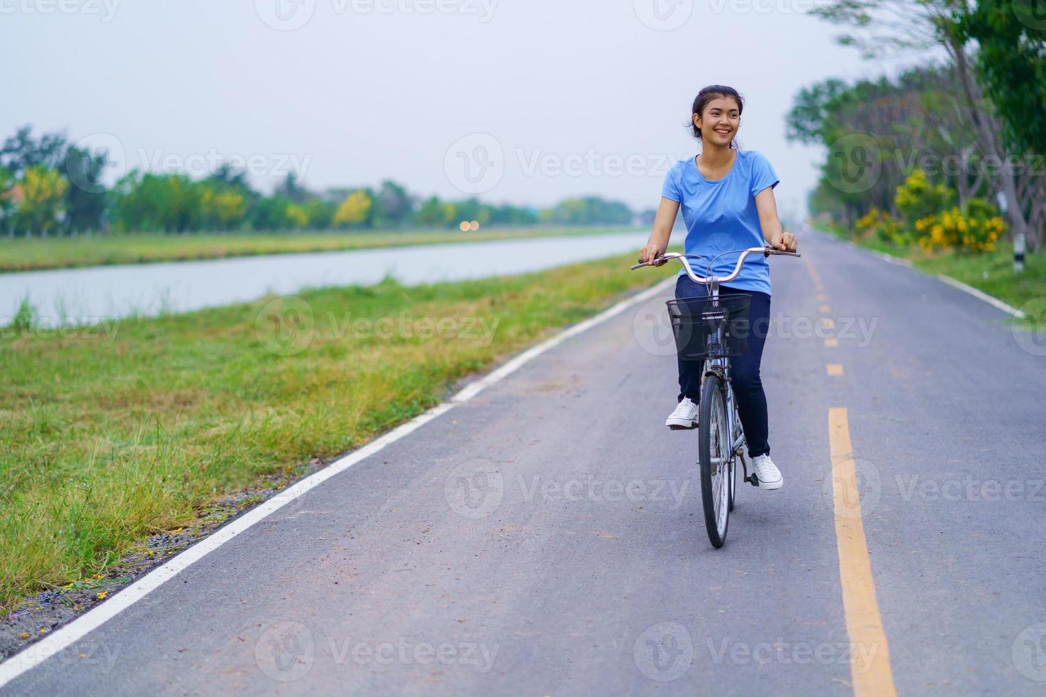 menina com bicicleta, mulher andando de bicicleta na estrada em um parque foto