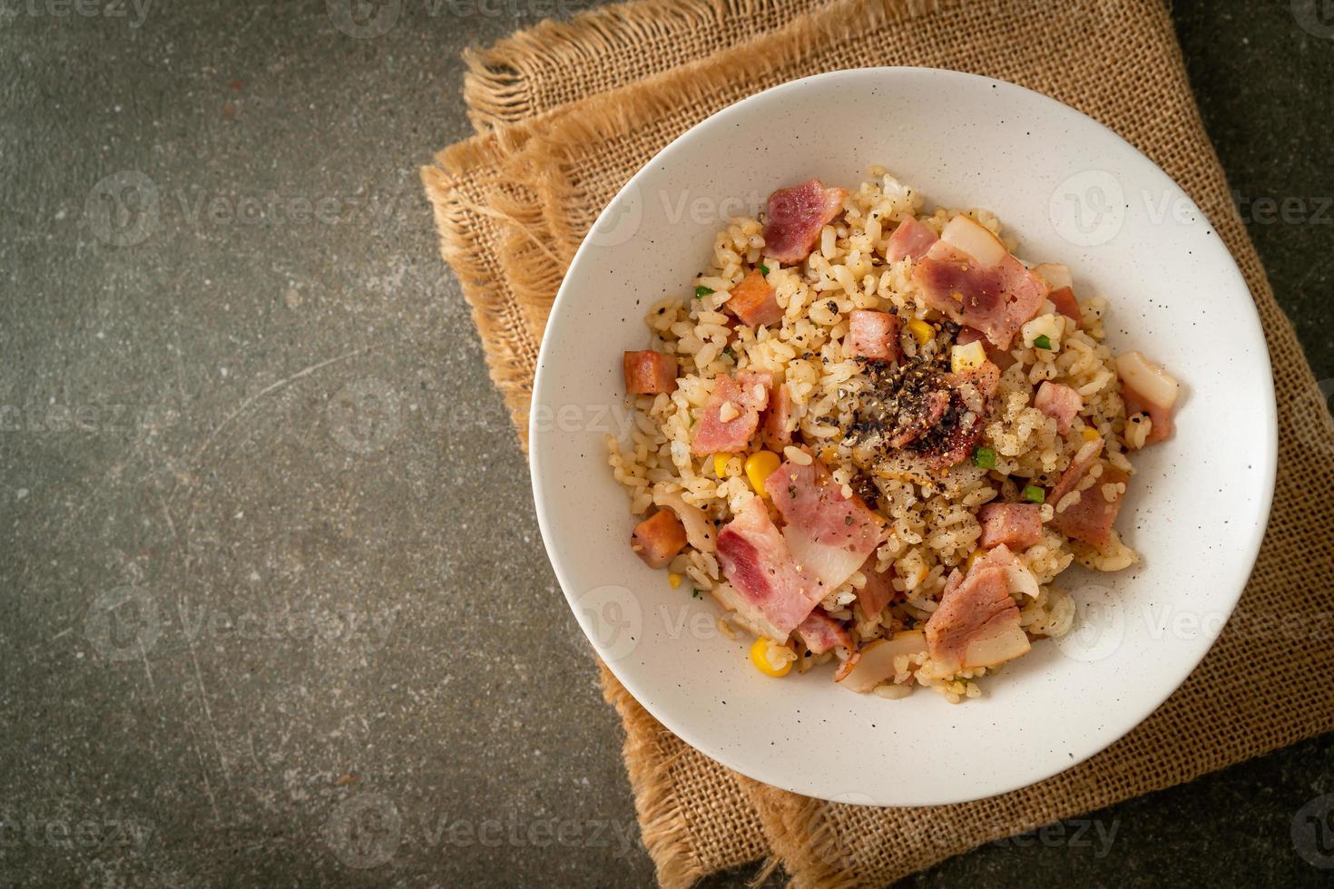 arroz frito com bacon, presunto e pimentão preto em prato branco foto