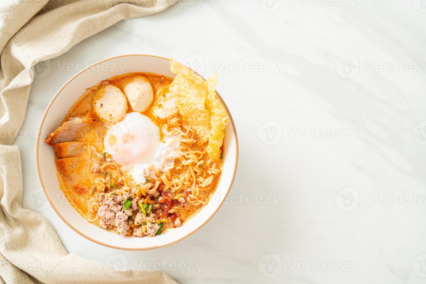 macarrão instantâneo com carne de porco e almôndegas em sopa picante ou macarrão tom yum em estilo asiático foto