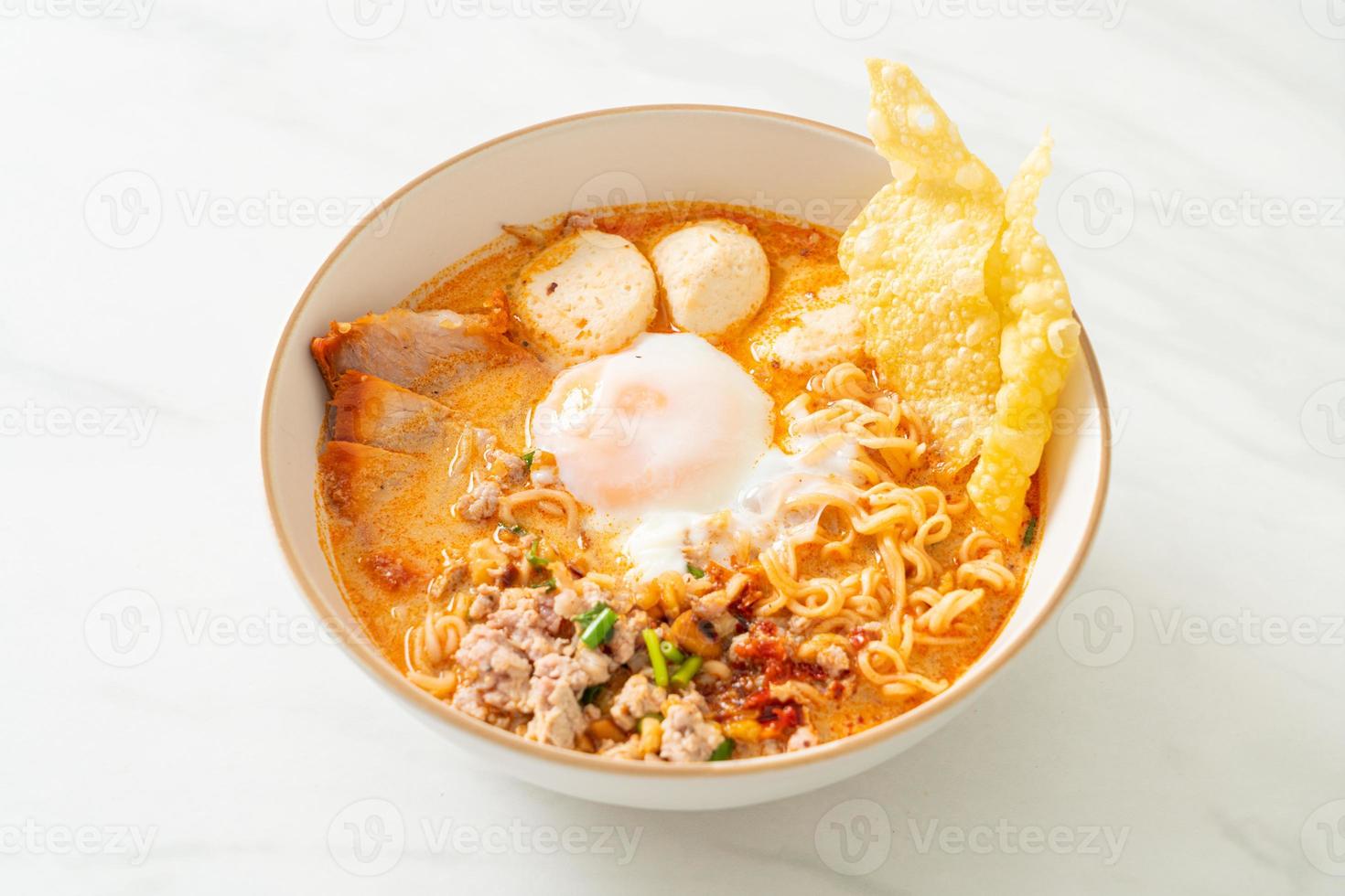 macarrão instantâneo com carne de porco e almôndegas em sopa picante ou macarrão tom yum em estilo asiático foto