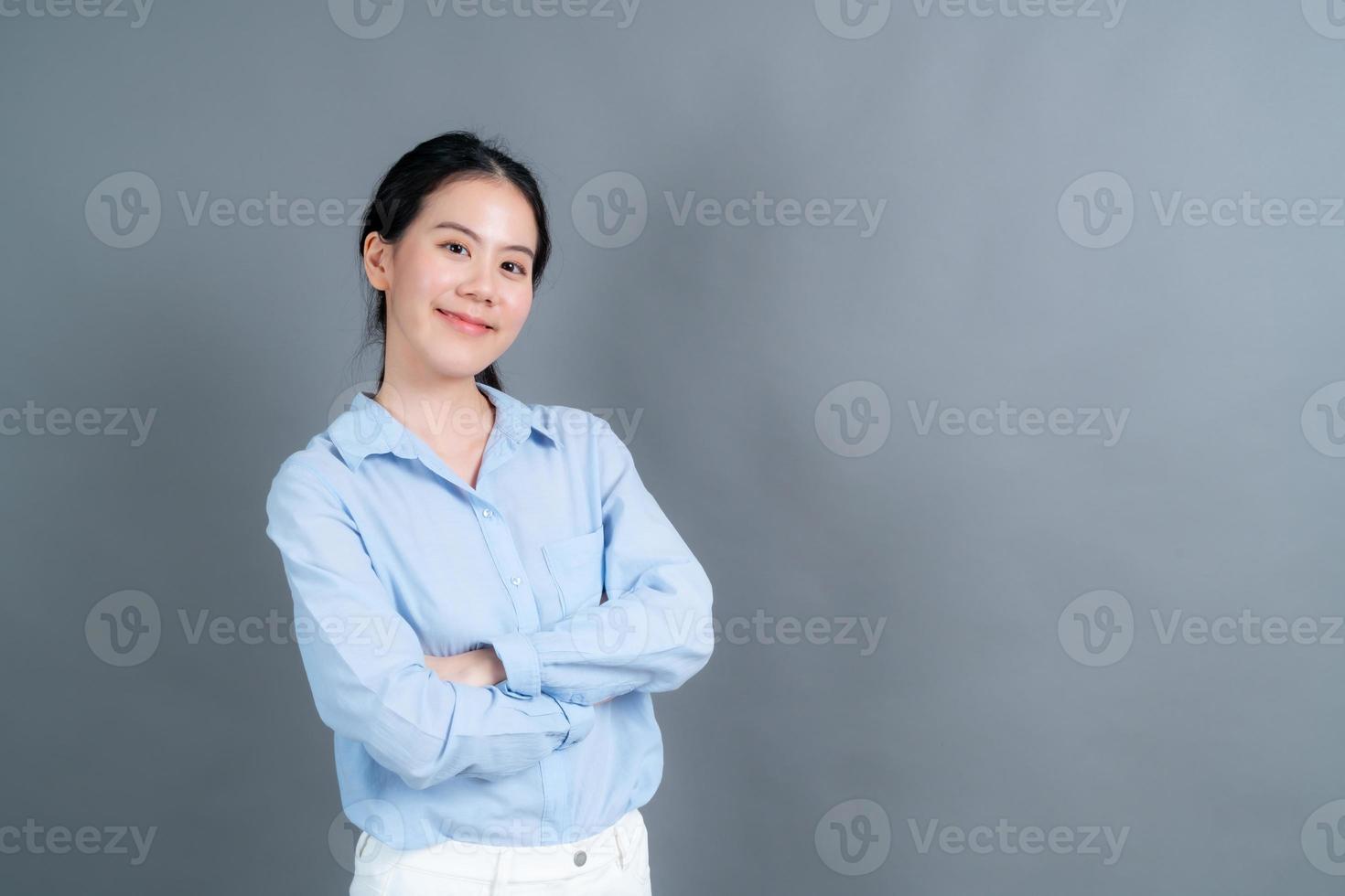 Mulher asiática feliz com uma carinha feliz em uma camisa azul em fundo cinza foto