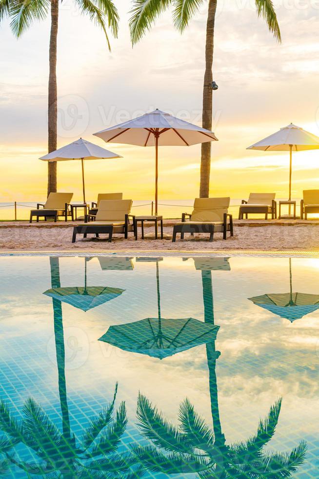 guarda-chuva e cadeira ao redor da piscina em hotel resort com nascer do sol pela manhã foto