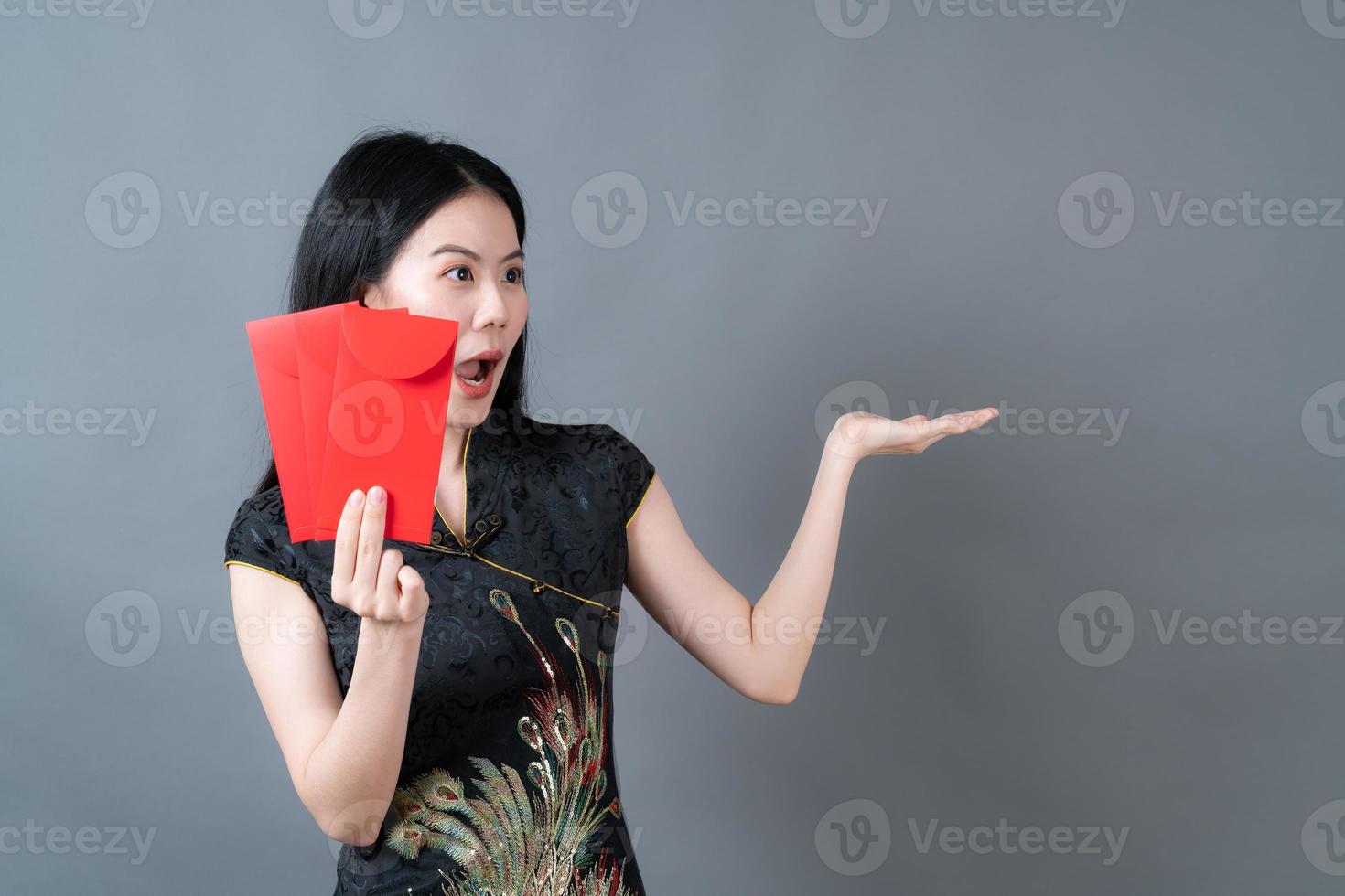 linda mulher asiática usa vestido tradicional chinês com envelope vermelho ou pacote vermelho sobre fundo cinza foto