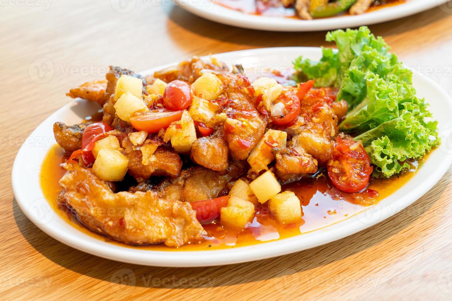 Garoupa frita coberta com molho doce, azedo e picante em prato branco - comida asiática foto