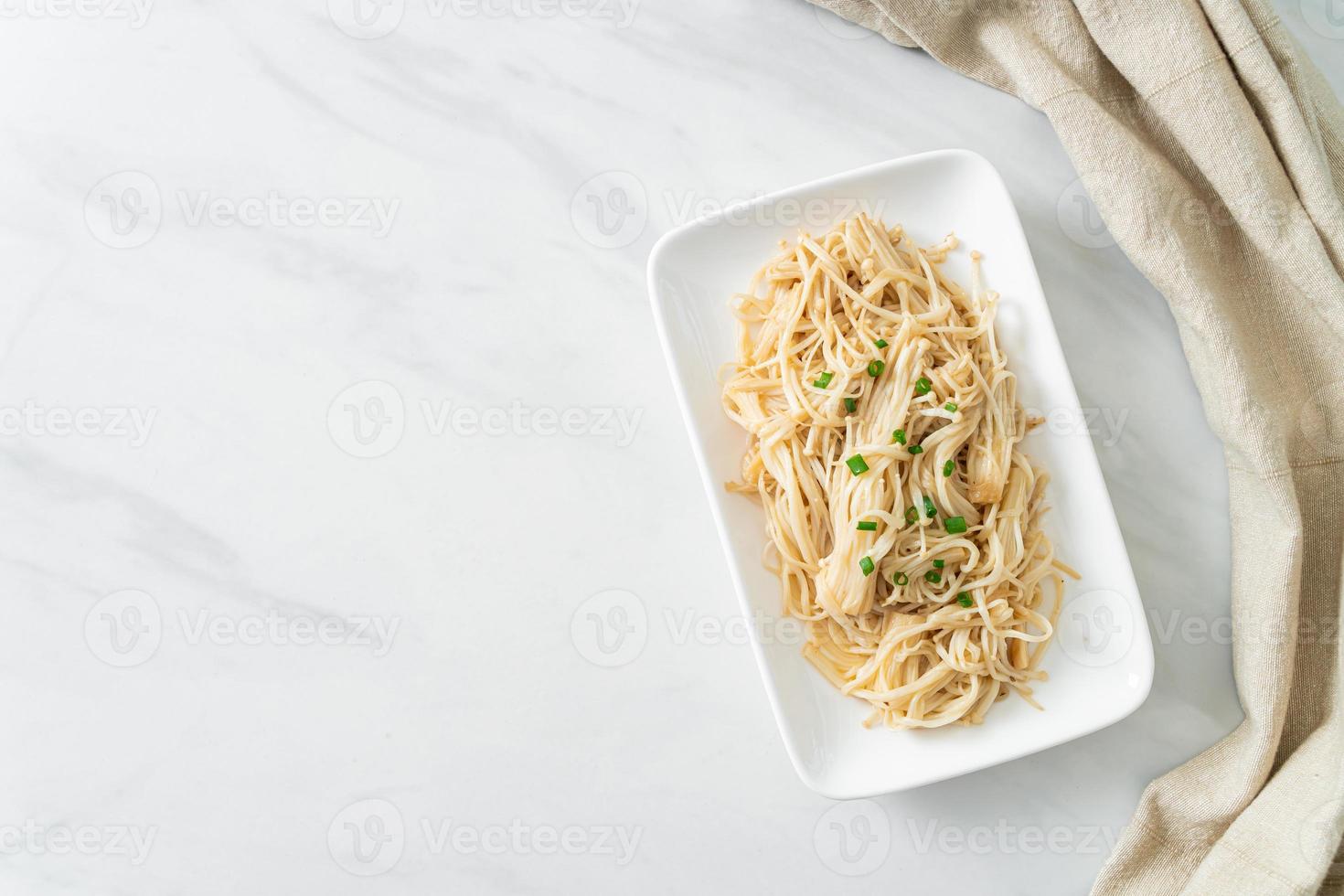 Cogumelo agulha dourado frito com manteiga no prato branco foto